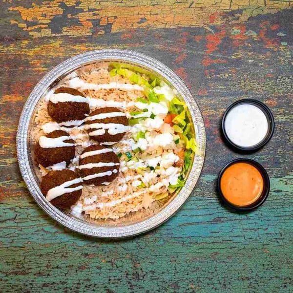 DC BITES halal falafel platter with rice, salad, white sauce, and orange sauce.