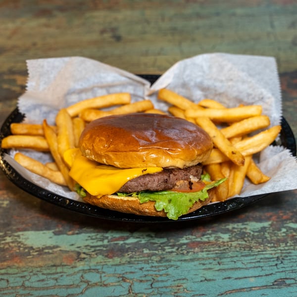 A DC BITES halal cheeseburger with lettuce and tomato, served with a side of golden fries.