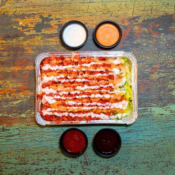 DC BITES halal chicken over rice with white sauce, hot sauce, and BBQ sauce.